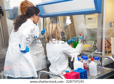 Photo of real female scientists researching in laboratory.Photo taken behind the glass.