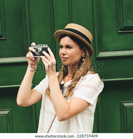 young attractive woman in hat, white dress, red bag and retro camera poses against Paris. Fashion and city style. Photo with instagram style filters