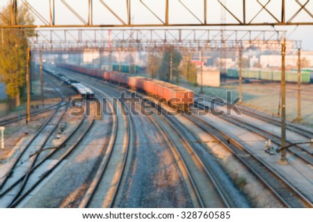 Blurred image of cargo train station on sunrise. Curve platform with containers