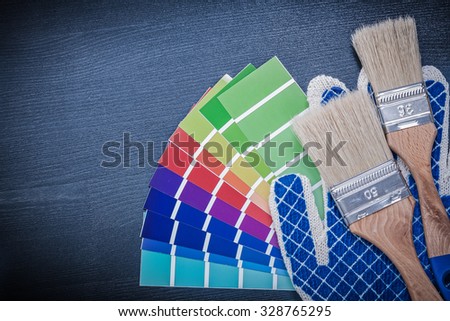 Paintbrushes pantone fan safety gloves on wooden board.