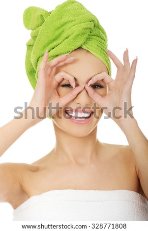 Young woman watching through fingers okay glasses.