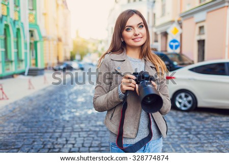 Happy woman on vacation photographing with a dslr camera on the city street
