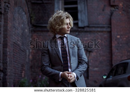 young man in suit taken aback by the problem,  portrait on  wall background