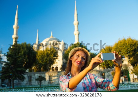 Girl in the hat making selfie by the smartphone on the background of the Blue Mosque, Istanbul. Turkey