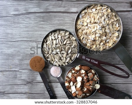 Ingredients in measuring cups and in measuring spoons; rolled oats, sunflower seeds, chopped almonds, cinnamon and himalayan salt Royalty-Free Stock Photo #328837046