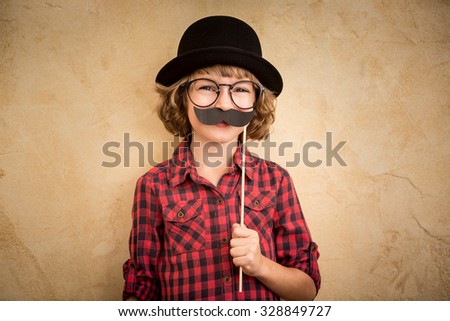 Funny kid with fake mustache. Happy child playing in home  Royalty-Free Stock Photo #328849727