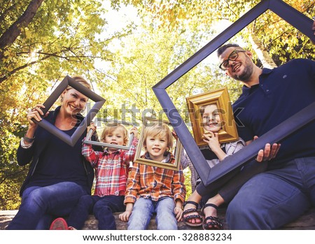 a cute family posing with picture frames in a park toned with a retro vintage instagram filter effect app or action