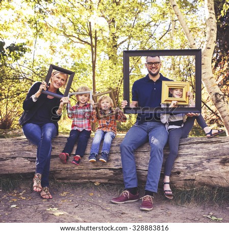 a cute family posing with picture frames in a park toned with a retro vintage instagram filter effect app or action