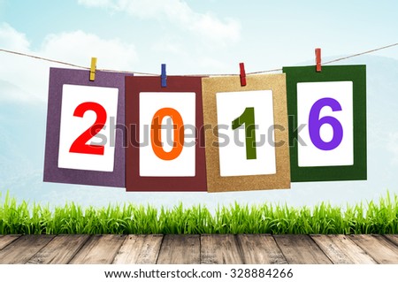 New year 2016 in photo frame hanging on clothesline with wood floor background