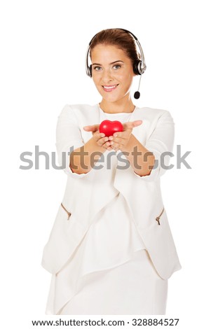 Happy call center woman with heart toy.