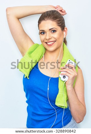Young woman with towel on neck after exercise. Smiling girl listening music with smartphone.