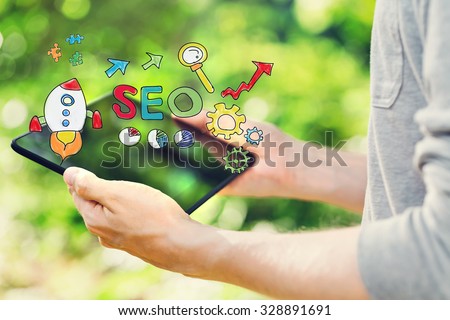 SEO concept with young man holding his tablet computer outside in the park