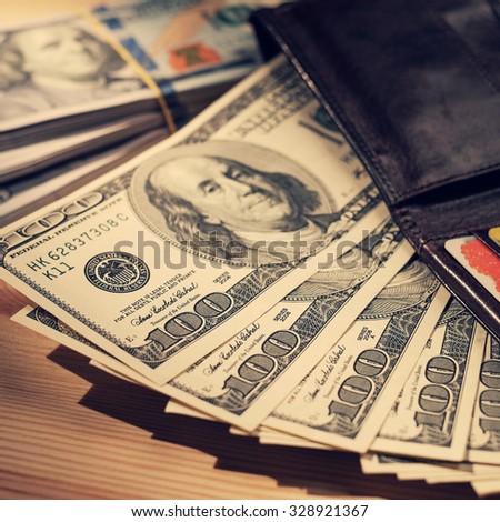 Brown Wallet with credit cards and one hundred dollars banknotes. Shallow depth of field. Retro vintage filtered hipster color image. Creative business finance making money concept .
