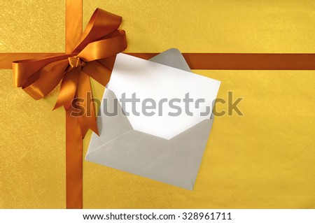 Christmas or birthday card, gold gift ribbon bow on shiny paper background, silver envelope , copy space