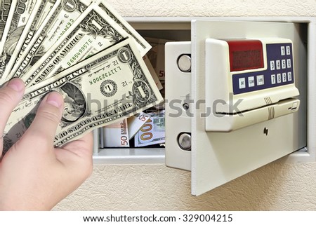 Steel safe with money and female hands holding dollars