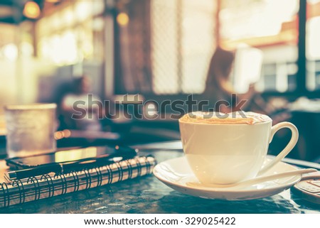 Cappuccino coffee on the table with blur coffee shop background, vintage tone 