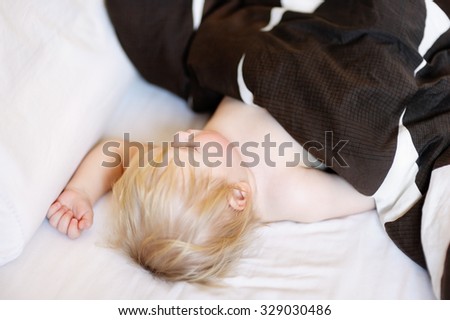 Adorable toddler boy sleeping in a bed