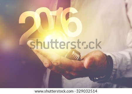 Happy new 2016 business year, businessman with light bulb and number 2016, retro toned image, selective focus. Royalty-Free Stock Photo #329032514