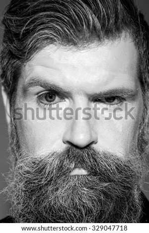 Portrait closeup view of one halloween holiday celebration character senior man with spooky painted face of zombi and long lush beard looking forward black and white, vertical picture