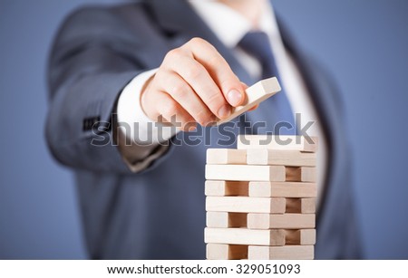 Unrecognizable businessman forming a wooden pyramid - closeup shot