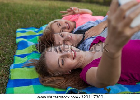 Beautiful young girl lying on the blanket and taking selfie