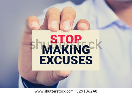 STOP MAKING EXCUSES, message on the card shown by a man