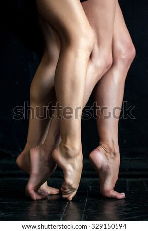 Close-up classic ballerina's legs on the black wooden floor 