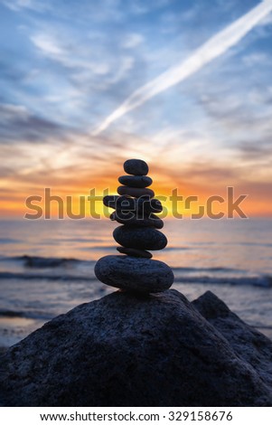 Stable pyramid of several stones of different shapes on a background of a bright sunset over the Baltic sea