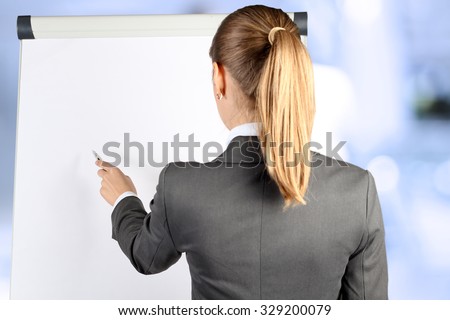 Over the shoulder view of blonde businesswoman pointing on a white board