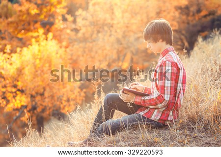 Young student working in autumn city park