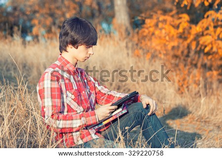 Young student working in autumn city park
