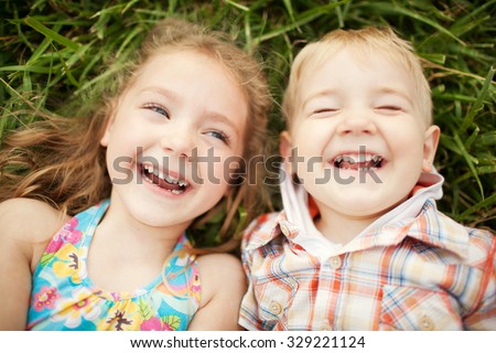 Top view portrait of two happy smiling kids lying on green grass. Cheerful brother and sister laughing together. Royalty-Free Stock Photo #329221124