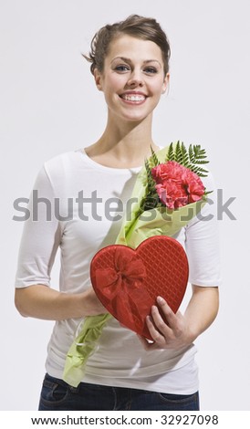 Attractive woman with flowers and heart-shaped candy box. Vertically framed shot.