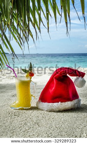 Cocktail "Boots Santa Claus" and the Santa Claus hat on the sand under a palm tree.