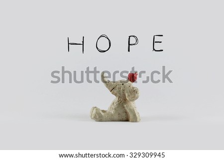 statue toy of smiling elephant with apple looking up over hope wordings background. Idea of happy, warm message concept for pattern background, card, decoration wallpaper, design template