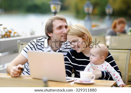 Happy parenthood: young parents with their sweet baby girl in outdoors cafe
