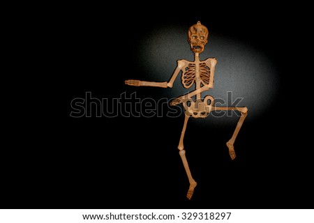 Brown skeleton man dancing on shiny black background 