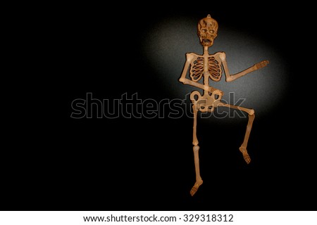 Brown skeleton man dancing on shiny black background 