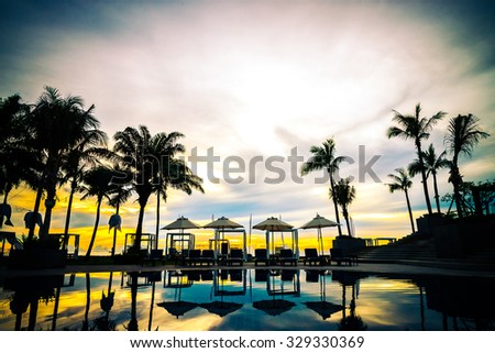Silhouette palm tree with umbrella chair pool in luxury hotel resort at sunrise times  - Vintage filter effect processing style pictures