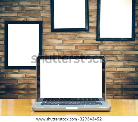 Computer notebook on brick wall background with advertise frame