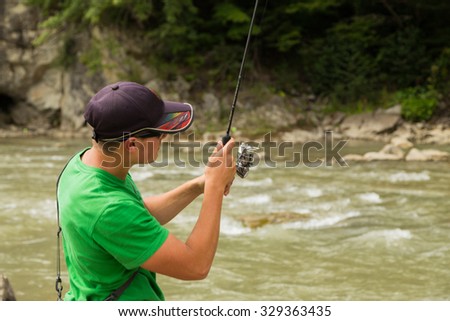 Fishing athlete on a mountain river. Fishing on the course. Trout fishing on spinninh. Photos for sporting and Natural magazines and websites. 