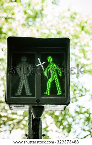 Green traffic light with drawn cross in the hand