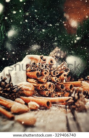 Christmas Food on Wooden Background. Sticks of Cinnamon in Linen Bag, Pine cones, Walnuts. Toned. Drawn snow