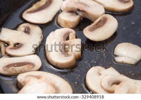 Chopped mushrooms in hot oil in a frying pan.