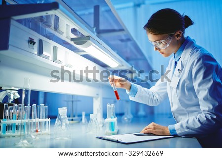 Young woman working with liquids in glassware Royalty-Free Stock Photo #329432669
