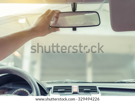 Hand adjusting rear view mirror. Royalty-Free Stock Photo #329494226