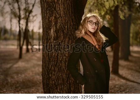 Blonde girl in big glasses in the autumn park