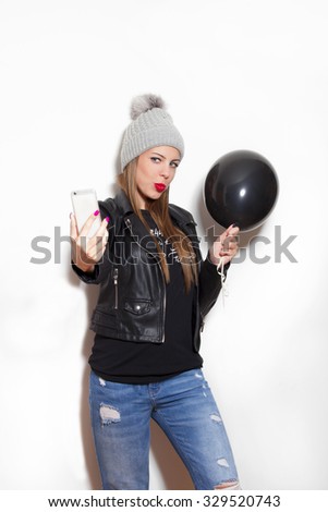 pretty young woman take a selfie in winter wool cap, leather jacket, hold black balloon