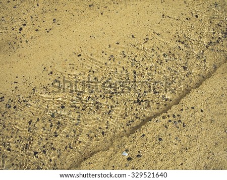 Brook on the sand beach low water. Rolling grains. Background like the aquarium. Orzola bay, Lanzarote, Canary Islands