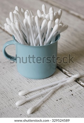 cotton buds in blue enamel cup on wooden table background.